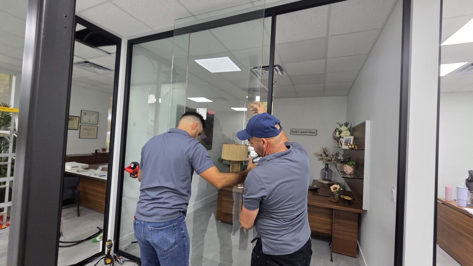 Dos instaladores trabajando sobre un panel de vidrio en el proyecto de SmartVinyl para Teilen en Miami.
